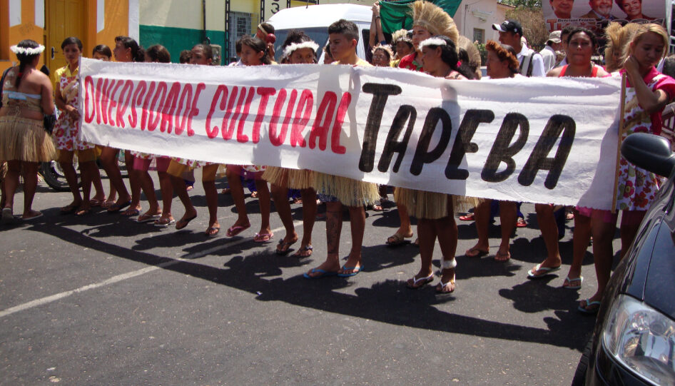Participantes da Comunidade Missionária Santíssima Trindade carregando uma faixa em protesto, defendendo a diversidade cultural.
