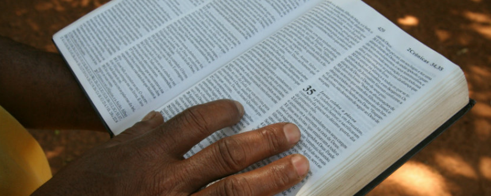 Mão em uma bíblia, simbolizando a reflexão bíblica Buscando as raízes do Deuteronômio.