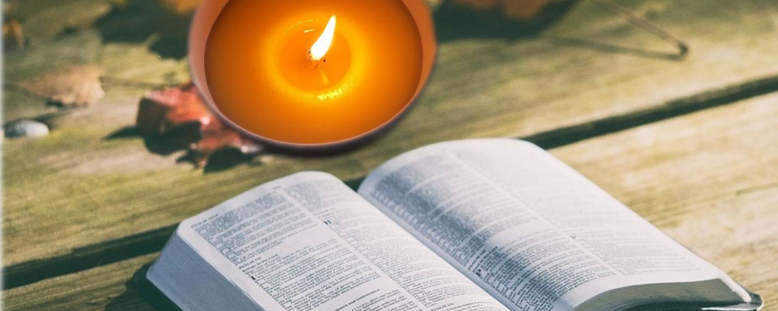 Foto de uma vela com a bíblia, representando a espiritualidade da Instituição.